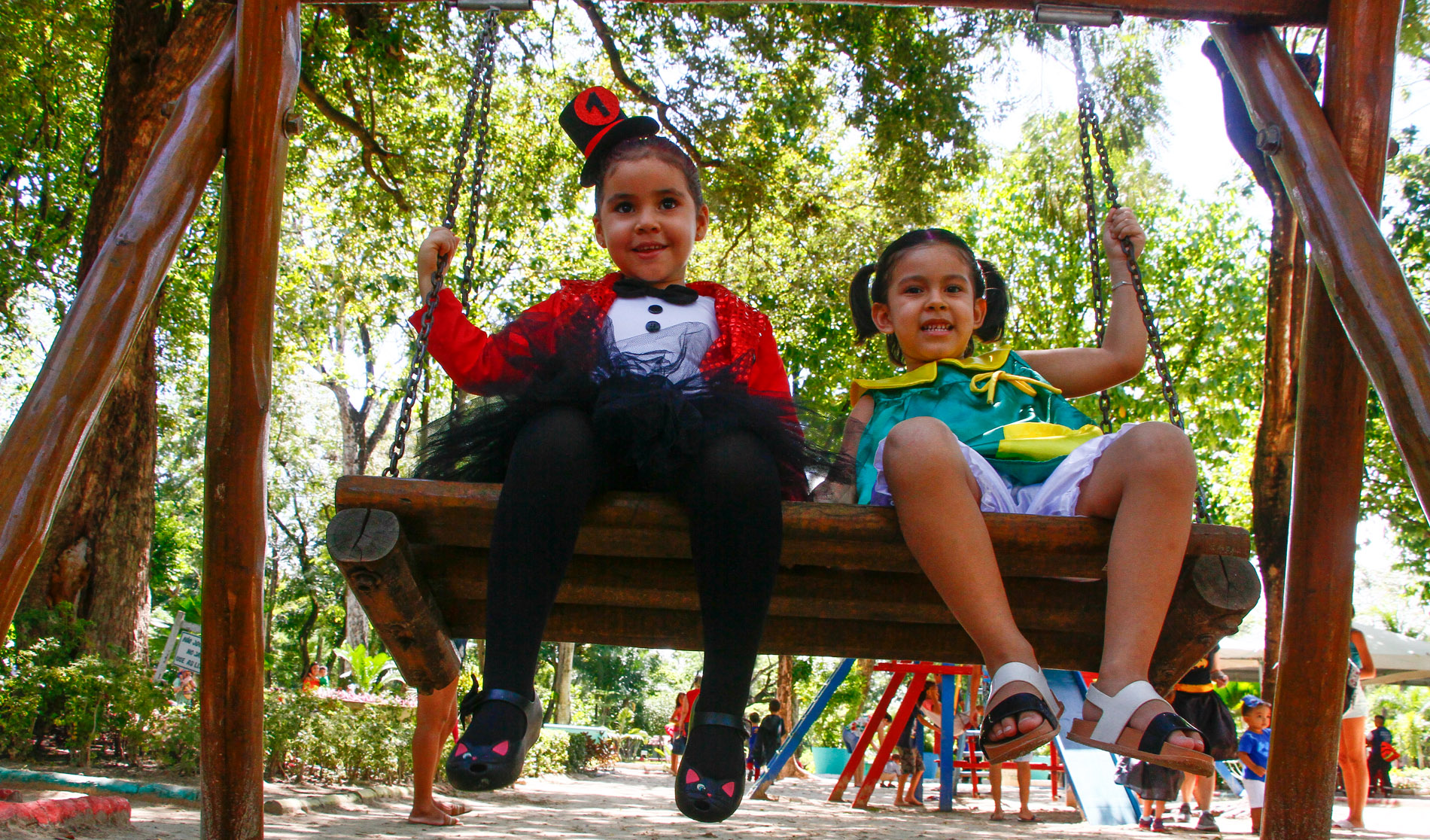 duas meninas fantasiadas brincando em balanço